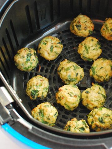 Air fryer chicken meatballs in the air fryer basket after cooking.
