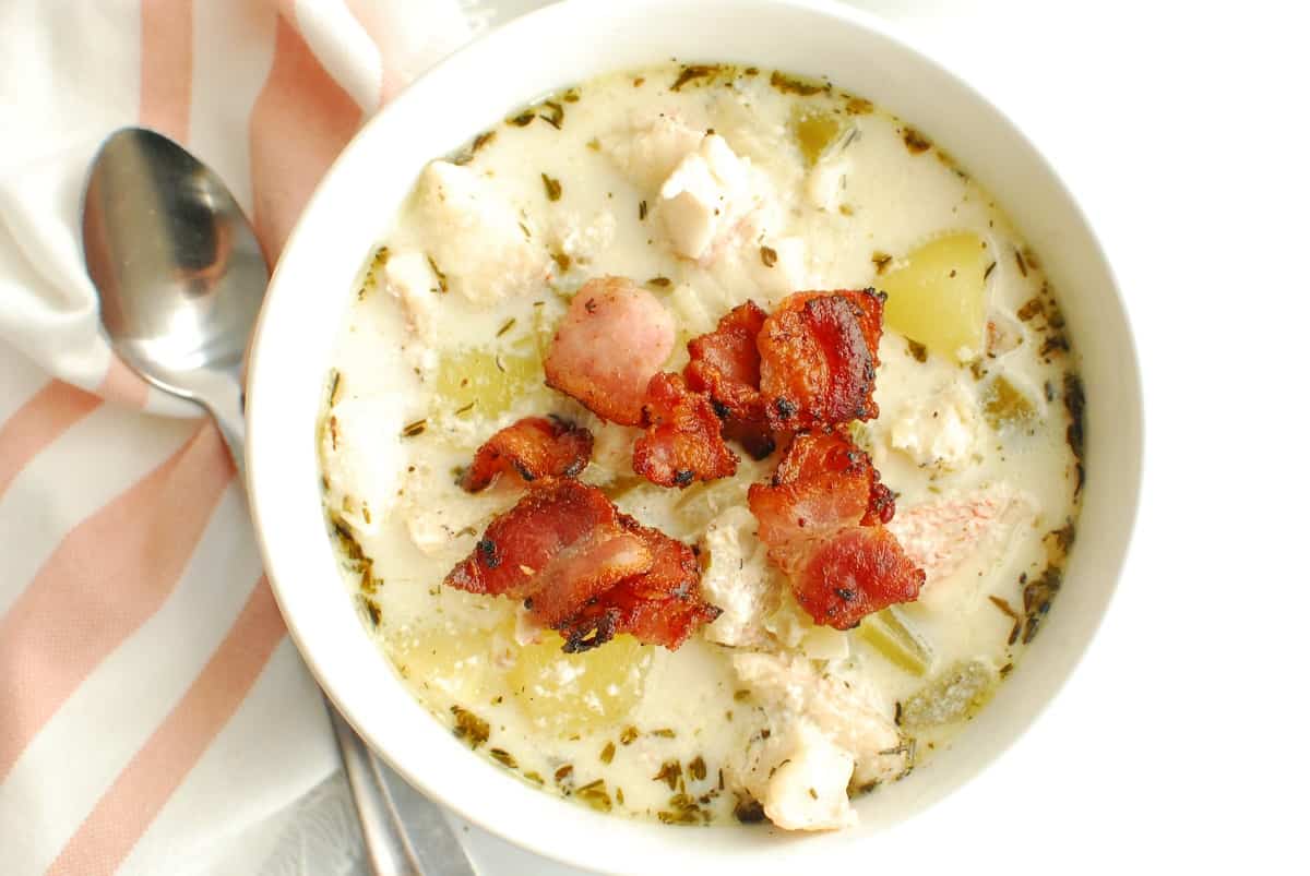 A bowl of redfish chowder garnished with bacon.