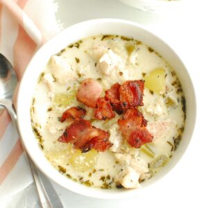 A bowl of redfish chowder next to a napkin and spoon.