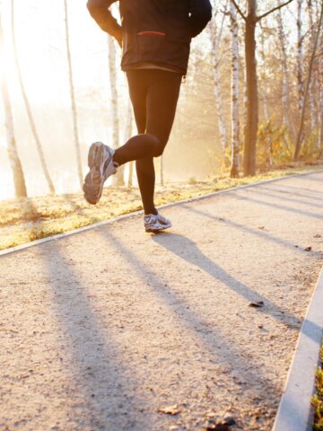 A man running on a path through the woods.