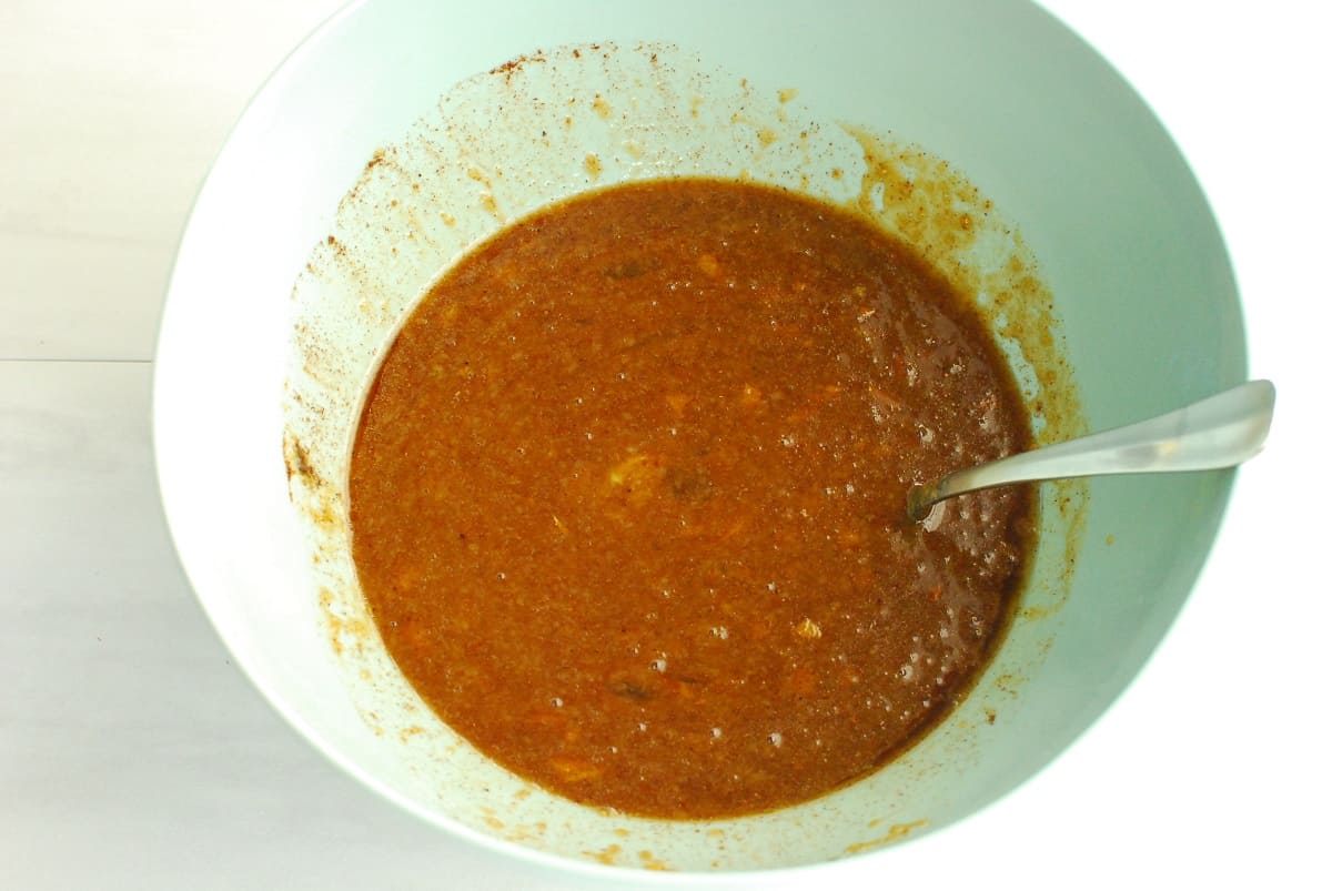 Eggs, applesauce, coconut sugar, olive oil, orange zest, vanilla, cinnamon, allspice, and nutmeg mixed together in a bowl.