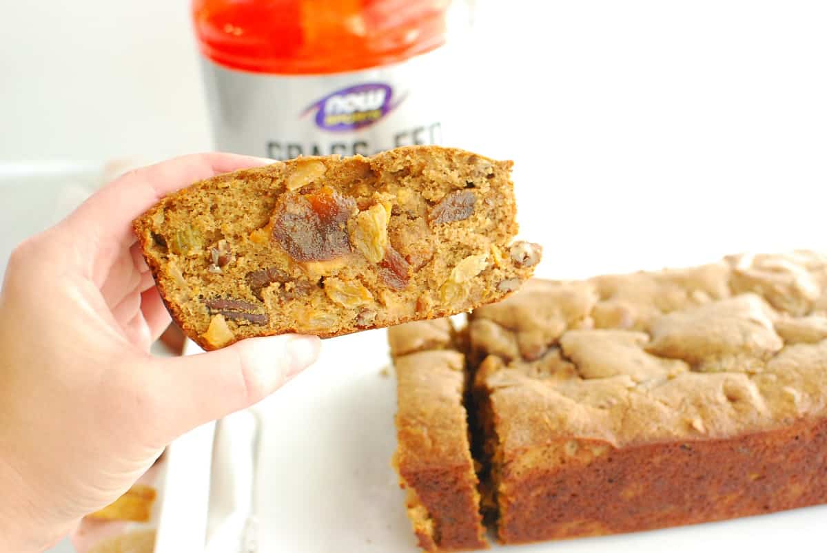 A woman holding a slice of healthy fruitcake.