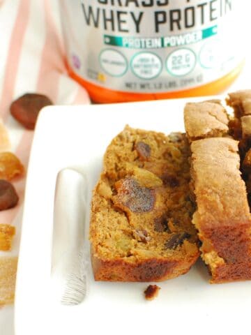 Healthy fruitcake with a slice cut into it on a white plate.