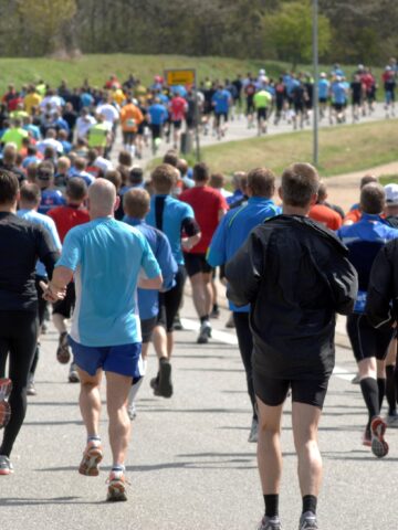 A large group of half marathon runners who are running along the street.