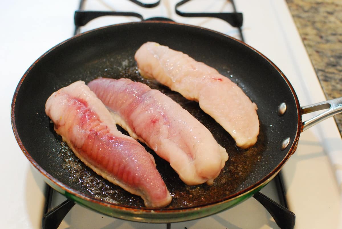 Monkfish sautéing in a pan.