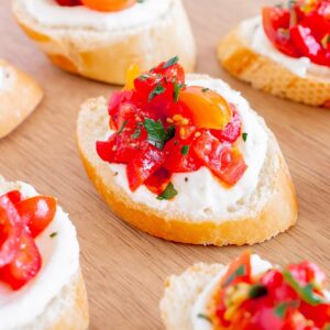 Whipped ricotta crostini on a wooden serving board.