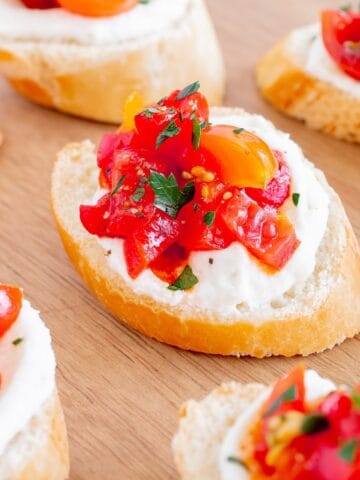 Whipped ricotta crostini on a wooden serving board.