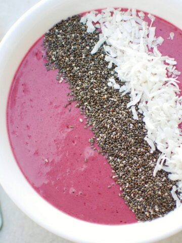 A thick cherry smoothie bowl topped with chia seeds and coconut.