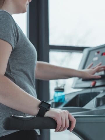 A woman pressing the button to start the treadmill.