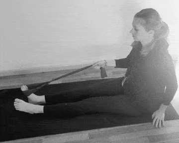 A woman doing an ankle inversion exercise with a resistance band.