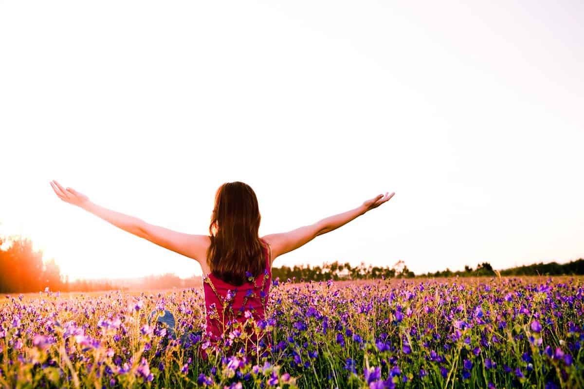 A woman standing outside in a field of flowers in the spring.