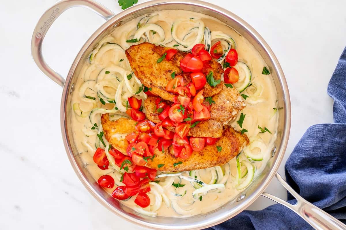 A sauté pan filled with creamy chicken and zoodles.