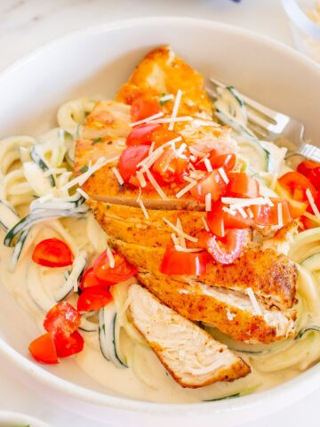 A bowl filled with creamy zoodles and cajun seasoned chicken.
