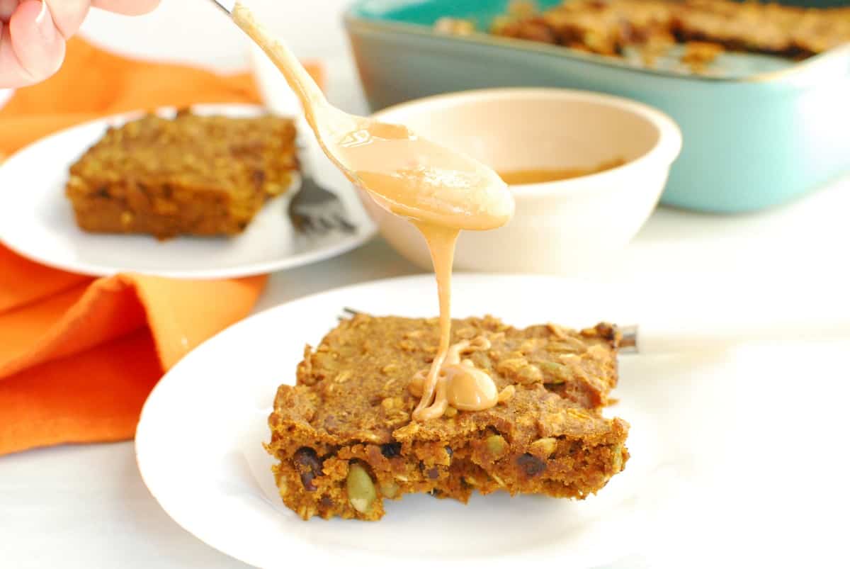 A healthy pumpkin breakfast bar being drizzled with peanut butter.