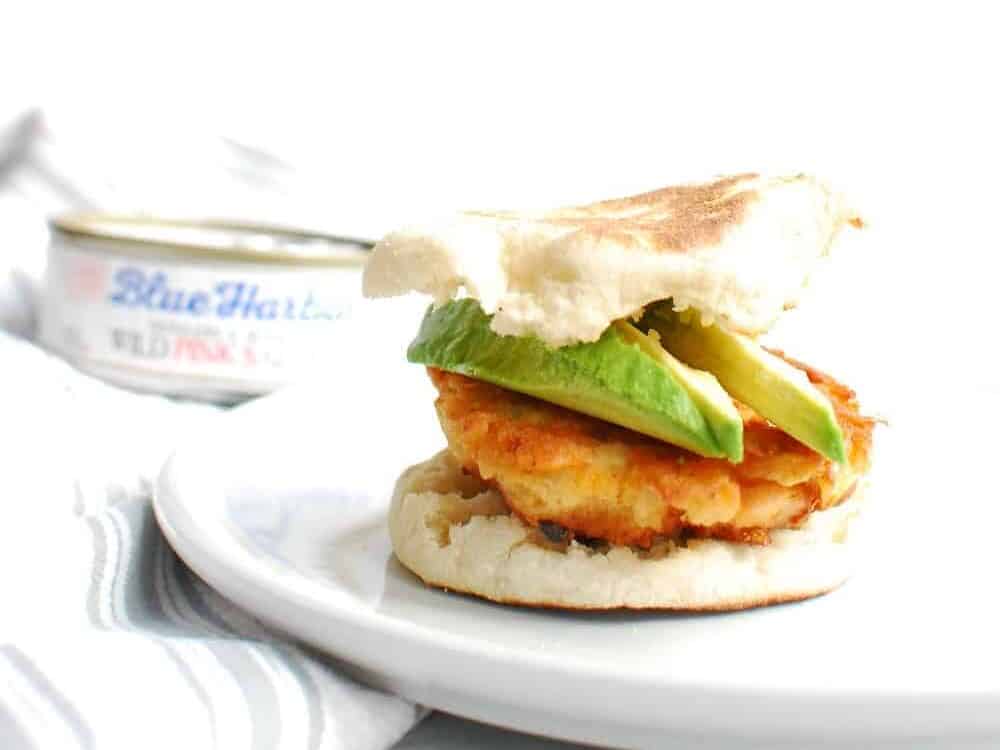 A salmon breakfast sandwich with avocado on a white plate.