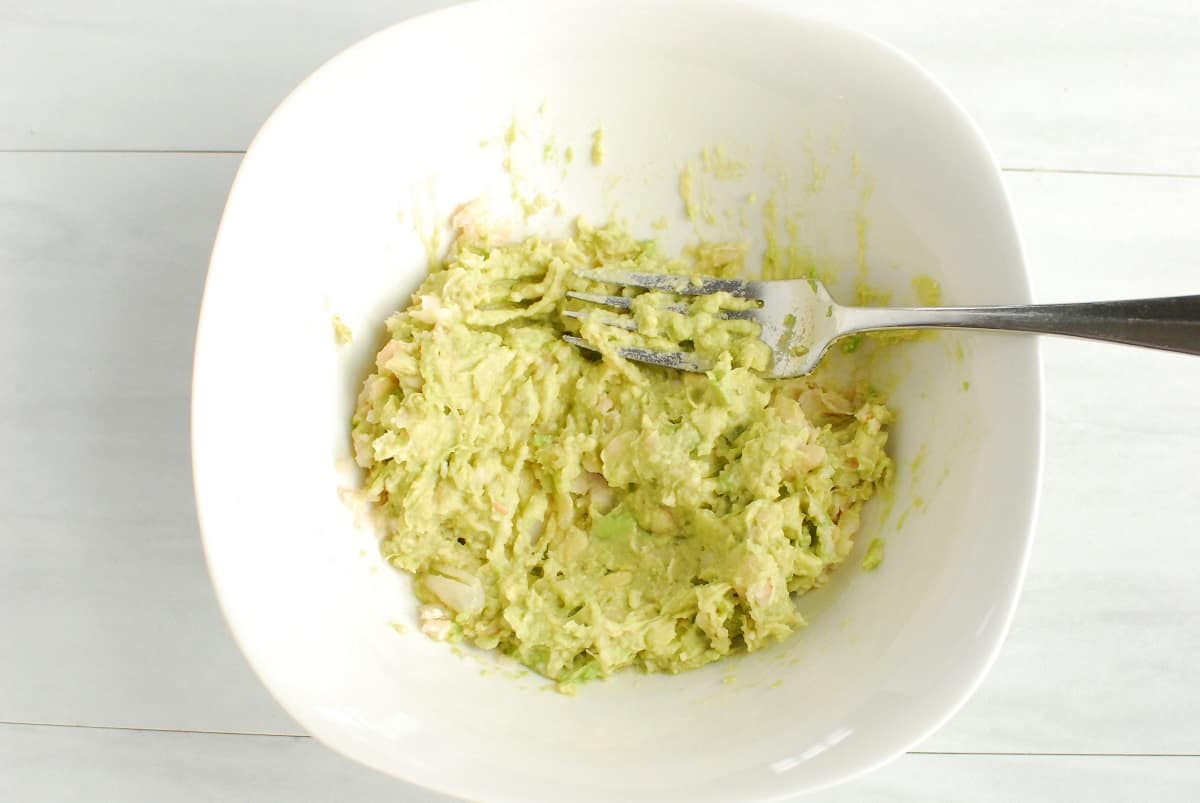 Avocado and white beans mashed together in a bowl.