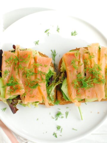 Two pieces of smoked salmon breakfast toast on a white plate.