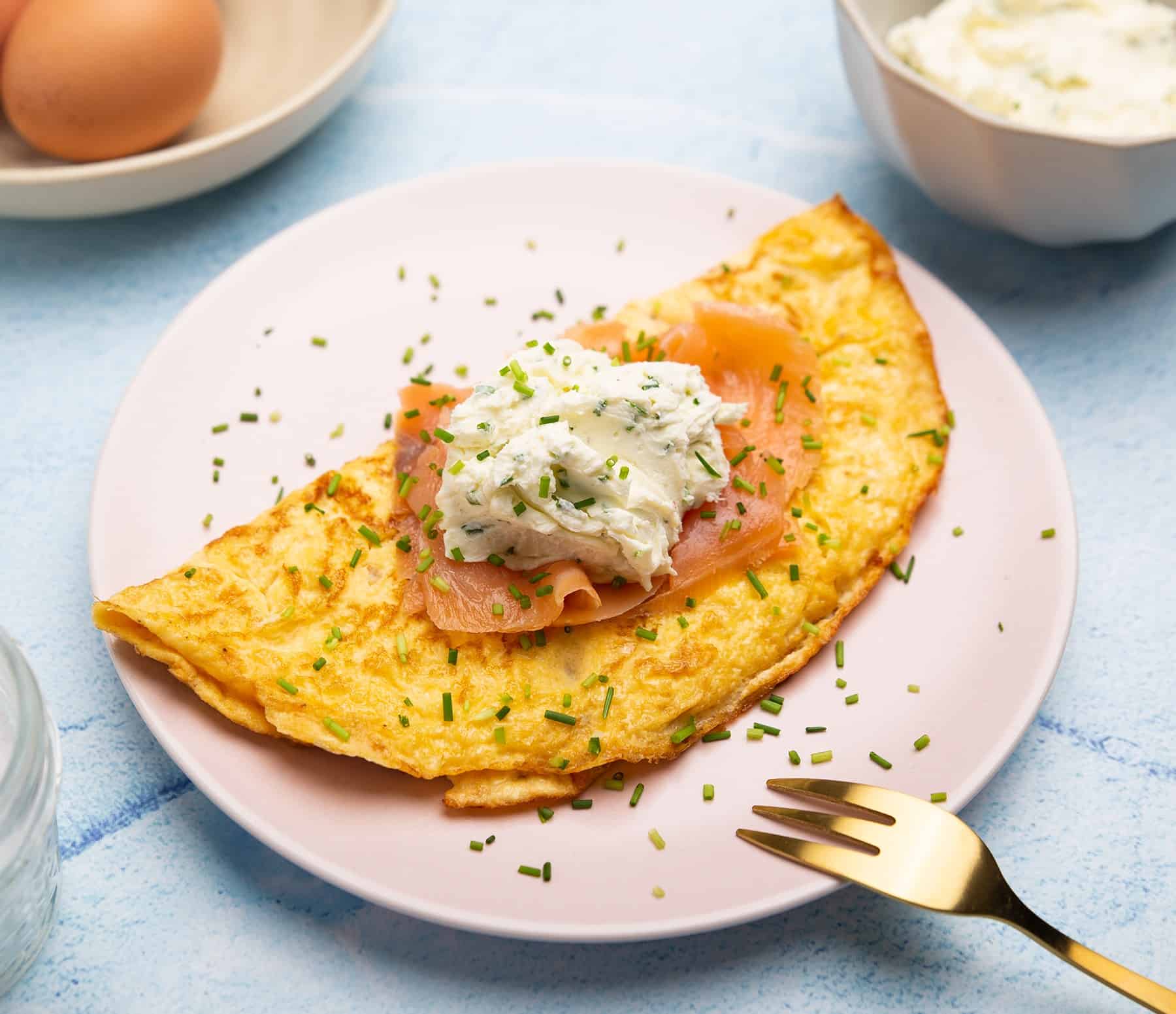 Omelet topped with smoked salmon on a white plate.