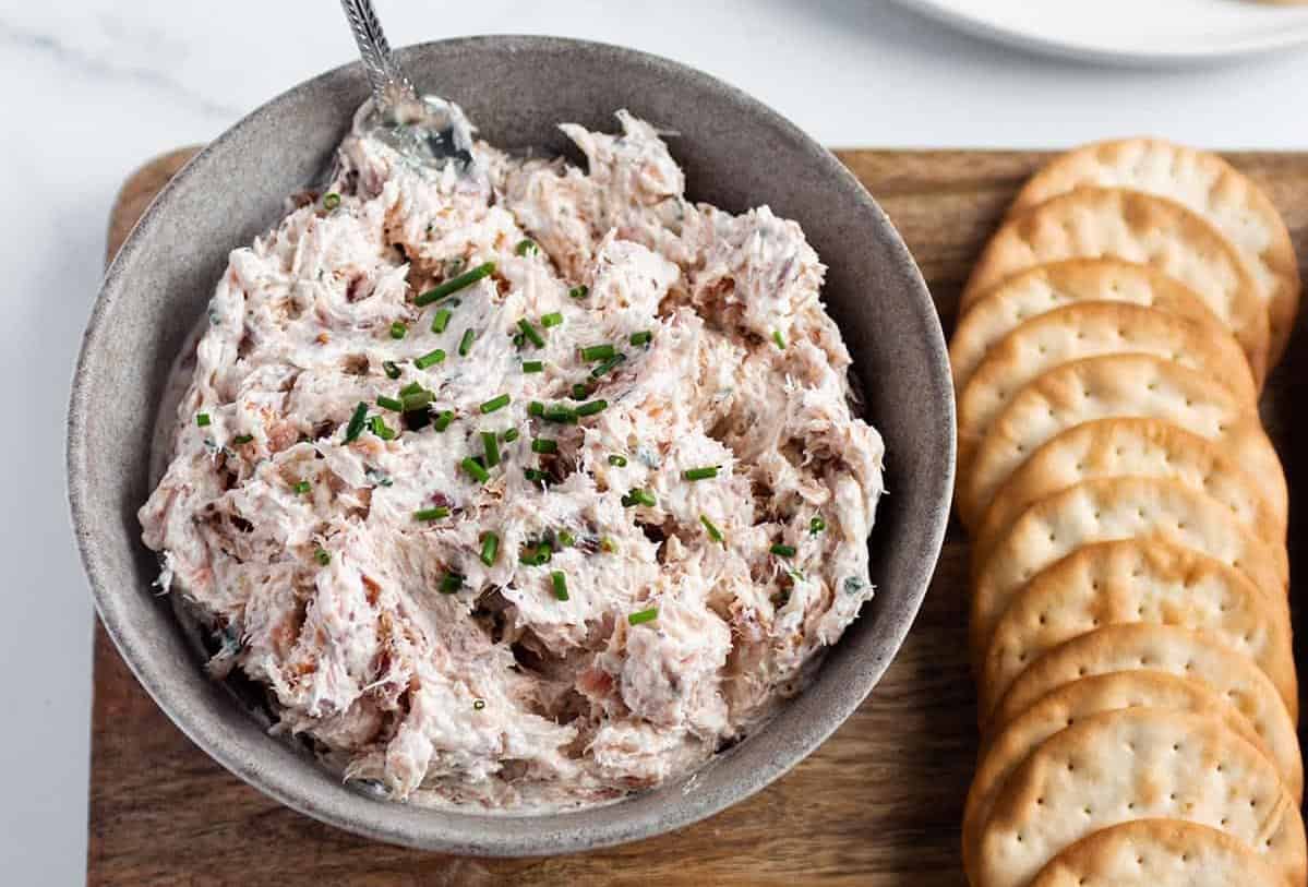 Smoked salmon dip in a bowl next to crackers.