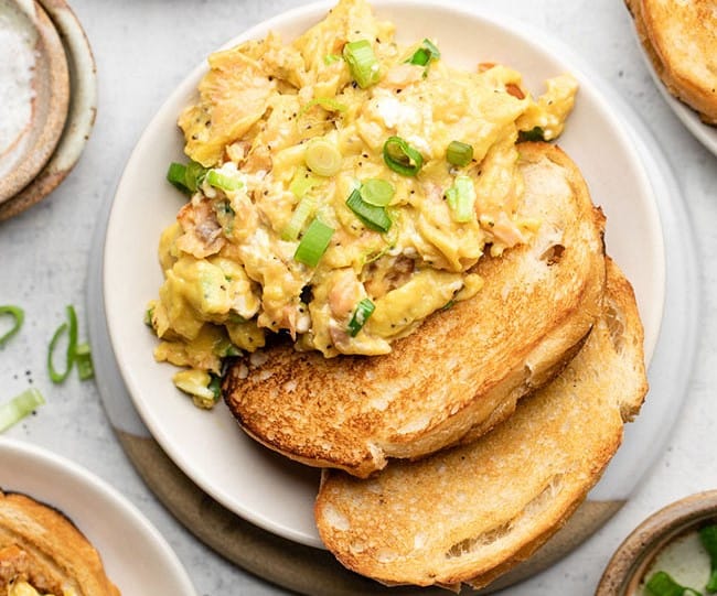 Salmon scrambled eggs next to two slices of toast.
