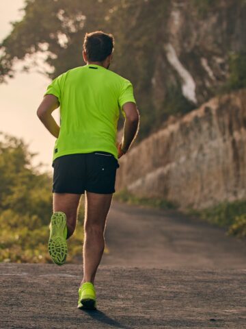 A man running outside on a nice day while training for a half marathon.