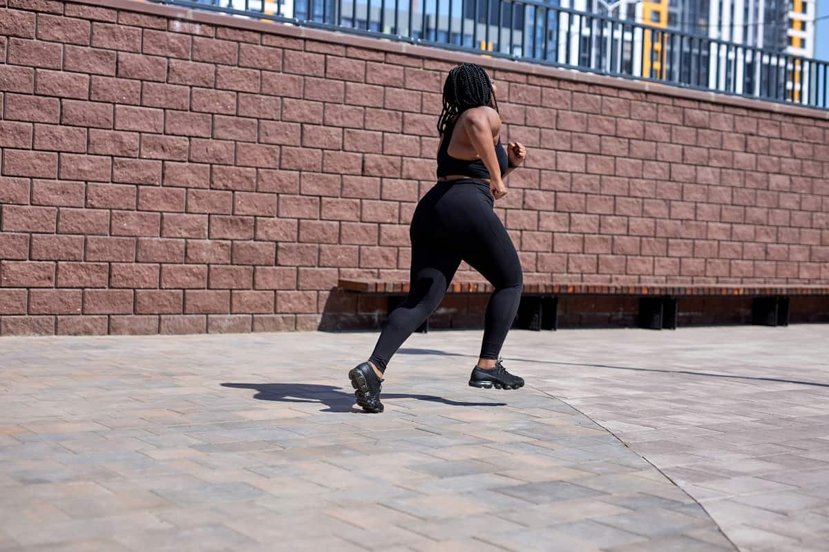 A woman running outside on a sidewalk.