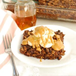 A piece of chocolate banana baked oatmeal on a plate, topped with sliced bananas and peanut butter.