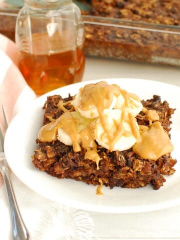 A piece of chocolate banana baked oatmeal on a plate, topped with sliced bananas and peanut butter.