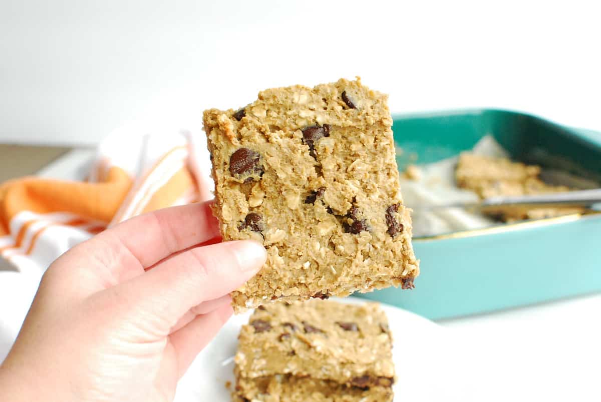 A woman's hand holding a gluten free oatmeal chocolate chip bar.