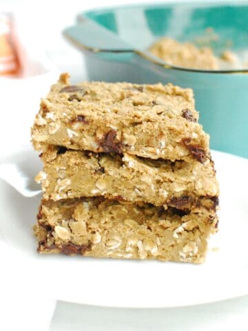 Three gluten free chocolate chip oatmeal bars stacked on a white plate.