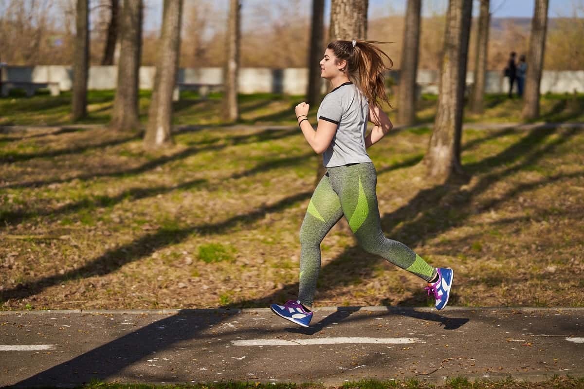 A female runner doing a tempo run on a park path.