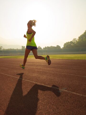A woman running on a track in the early morning.