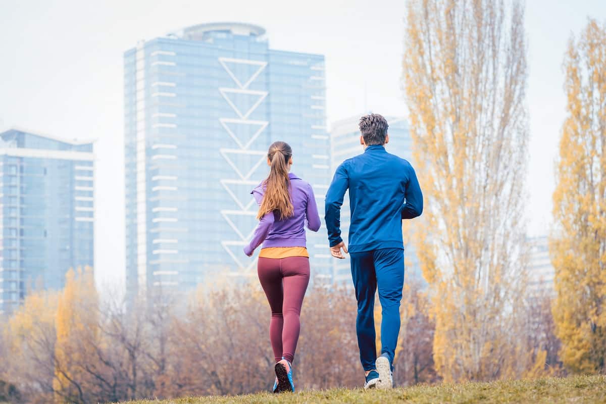 A couple running through a city park.