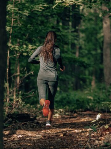 A woman running on a trail outdoors.