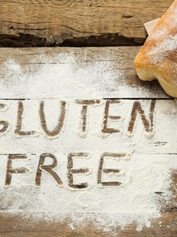 Flour on a wooden table with the words gluten free spelled out.