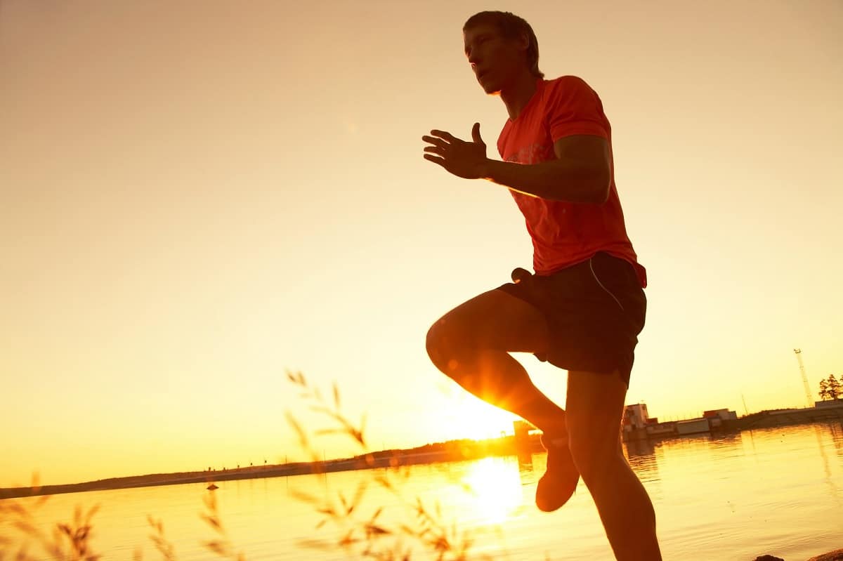 A male runner doing running drills outside at sunset.