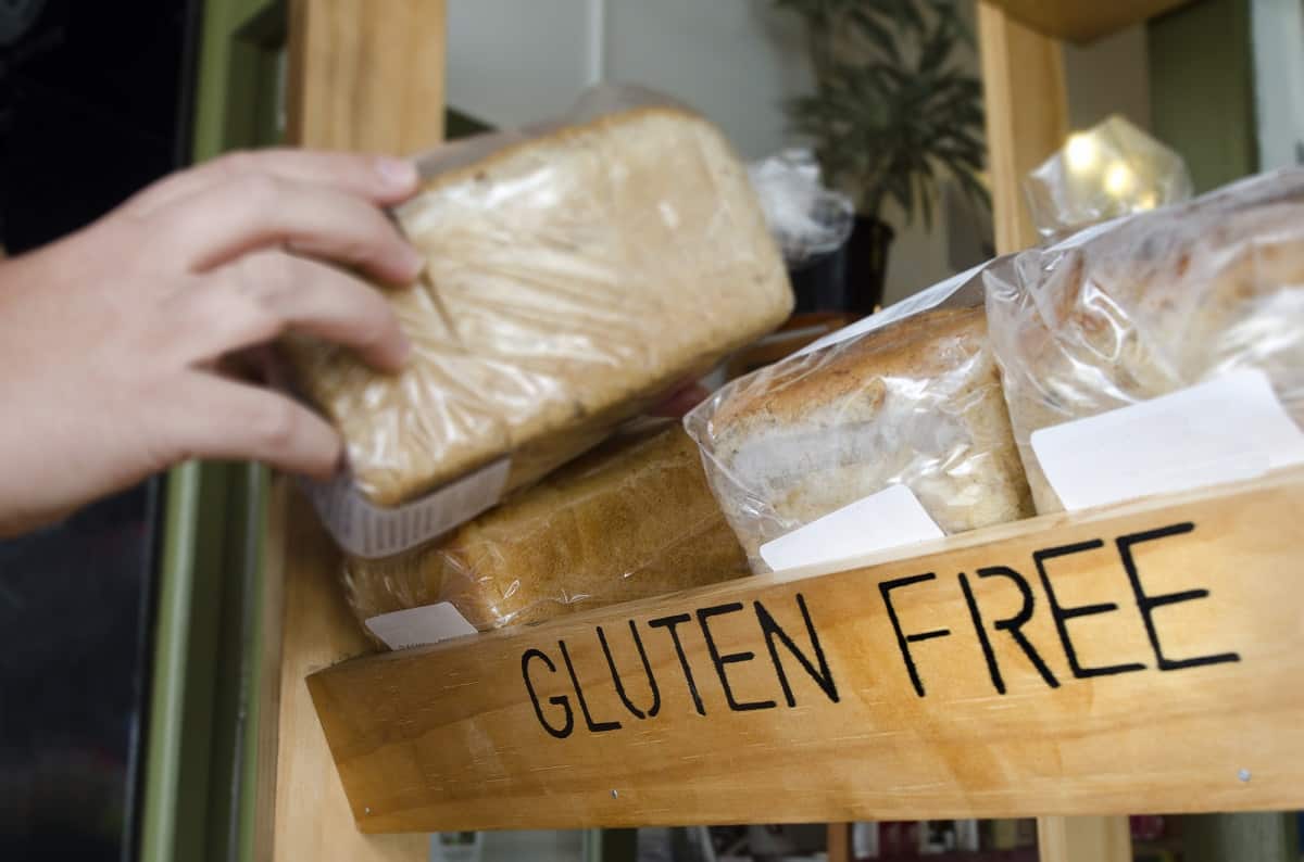 An athlete choosing a loaf of gluten free bread from a wooden shelf.