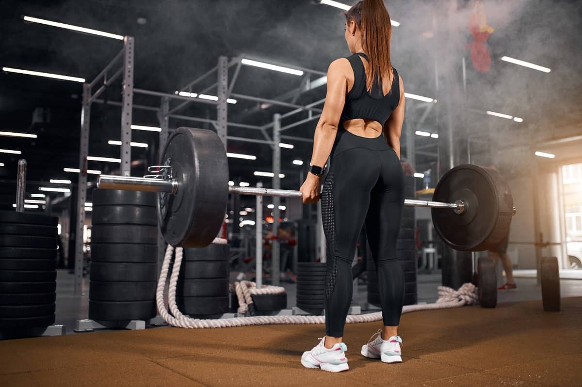 A woman doing deadlifts at a gym.