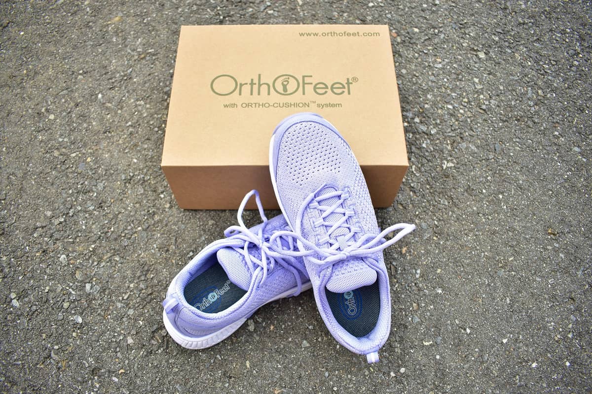A pair of purple Orthofeet sneakers leaning against the shoe box.