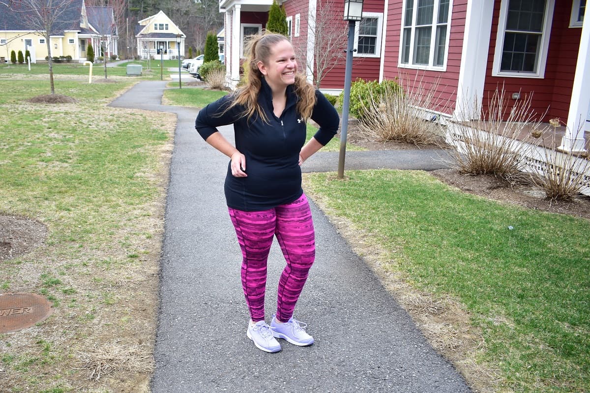 A woman standing outside on a sidewalk, wearing Orthofeet shoes.