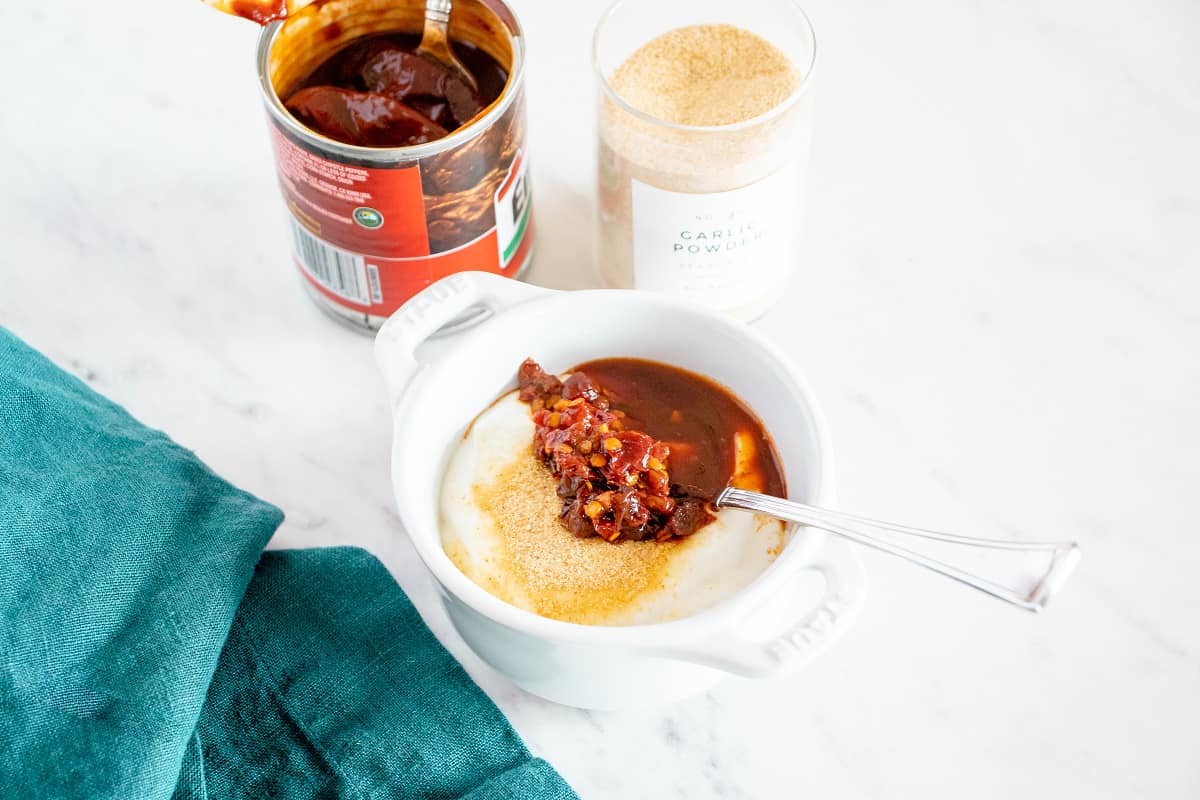 Greek yogurt, chipotle peppers, adobo, salt, and garlic powder added to a small white bowl.