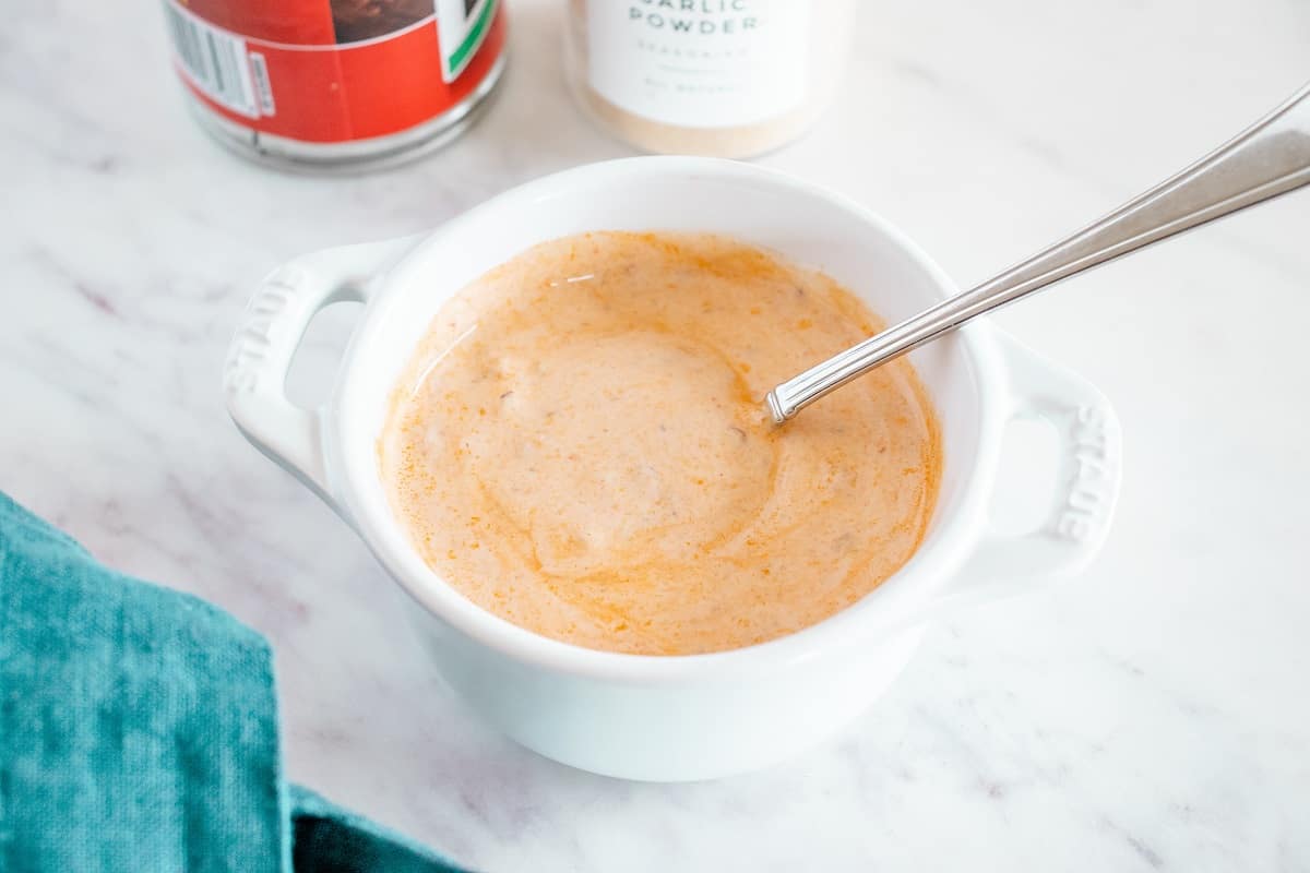 A small white bowl with chipotle greek yogurt taco sauce that has just been mixed.