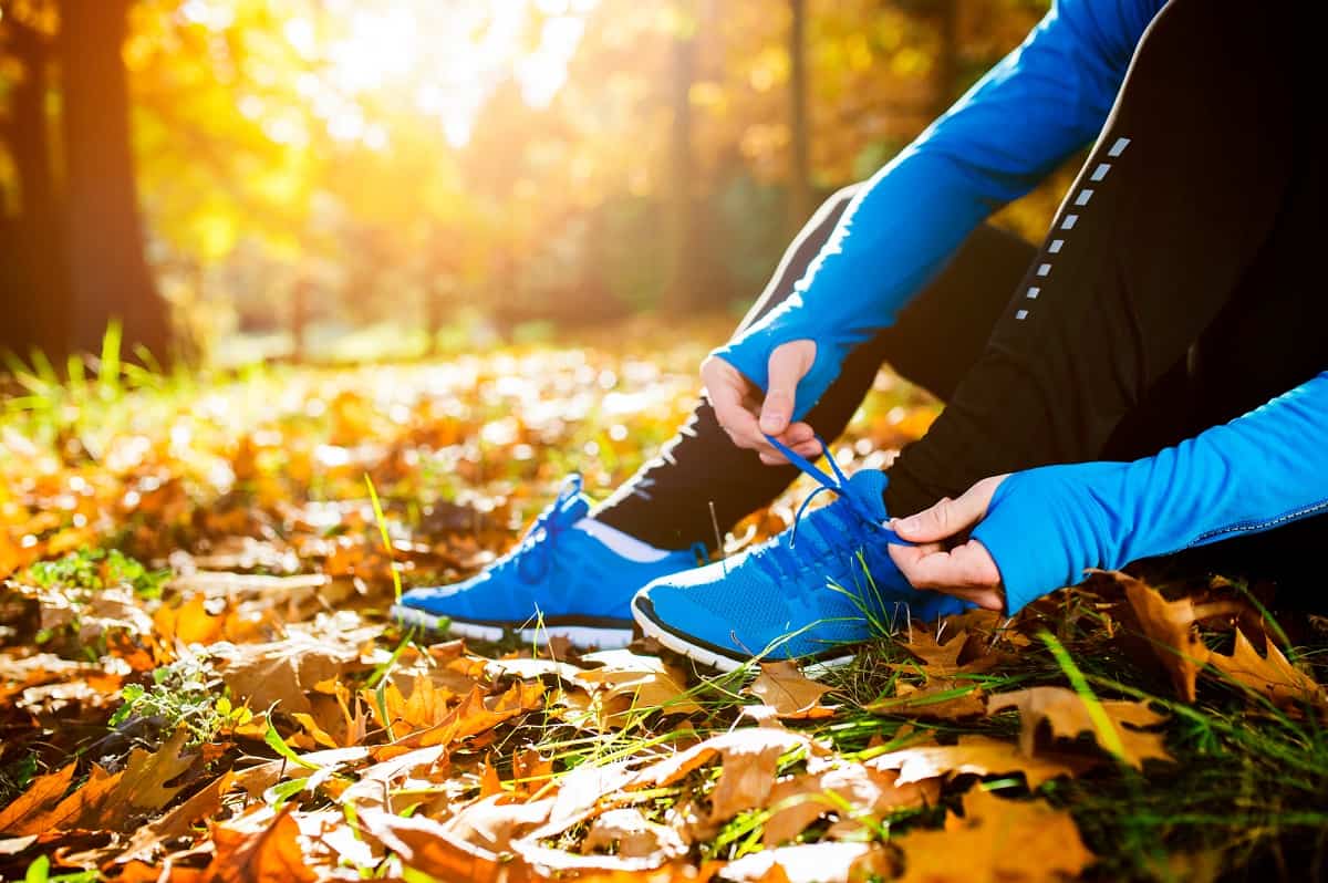 A man outside tying his shoes getting ready to do a fall half marathon training run.