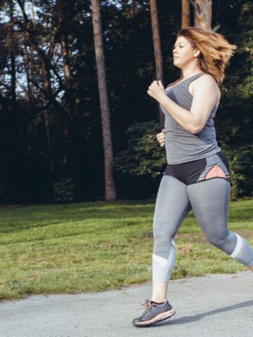 A woman running outside in a grey outfit, training for a half marathon.
