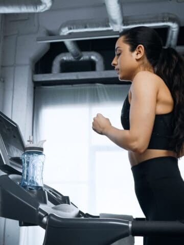 A woman in a black top running on a treadmill.