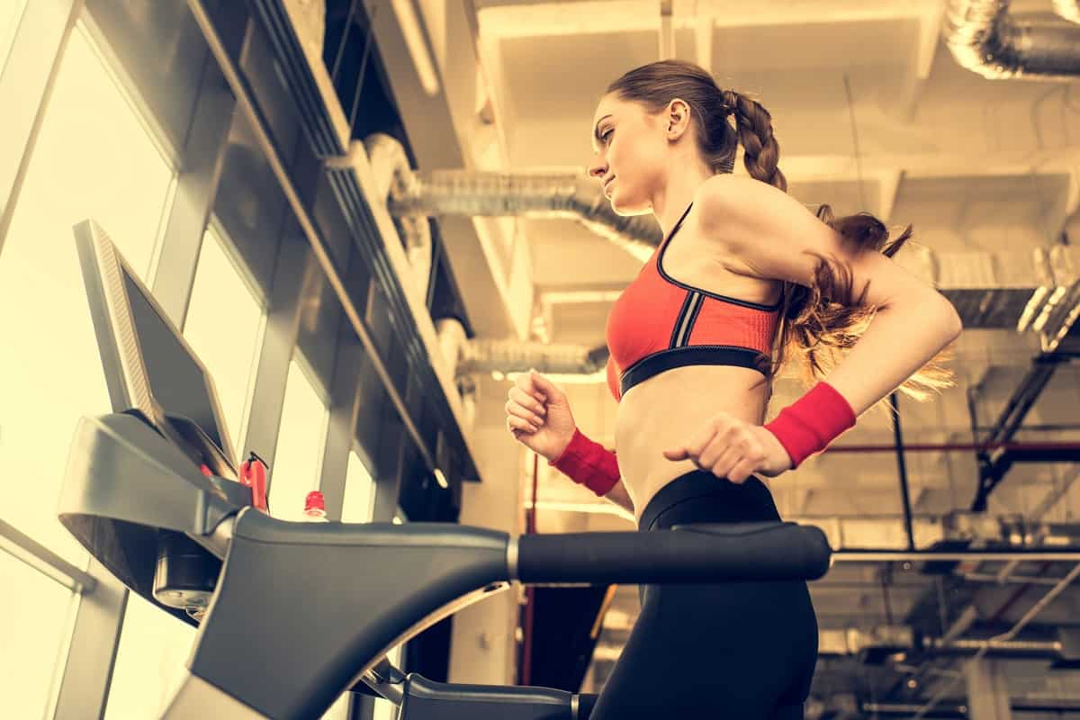 A woman in a pink top running on a treadmill.