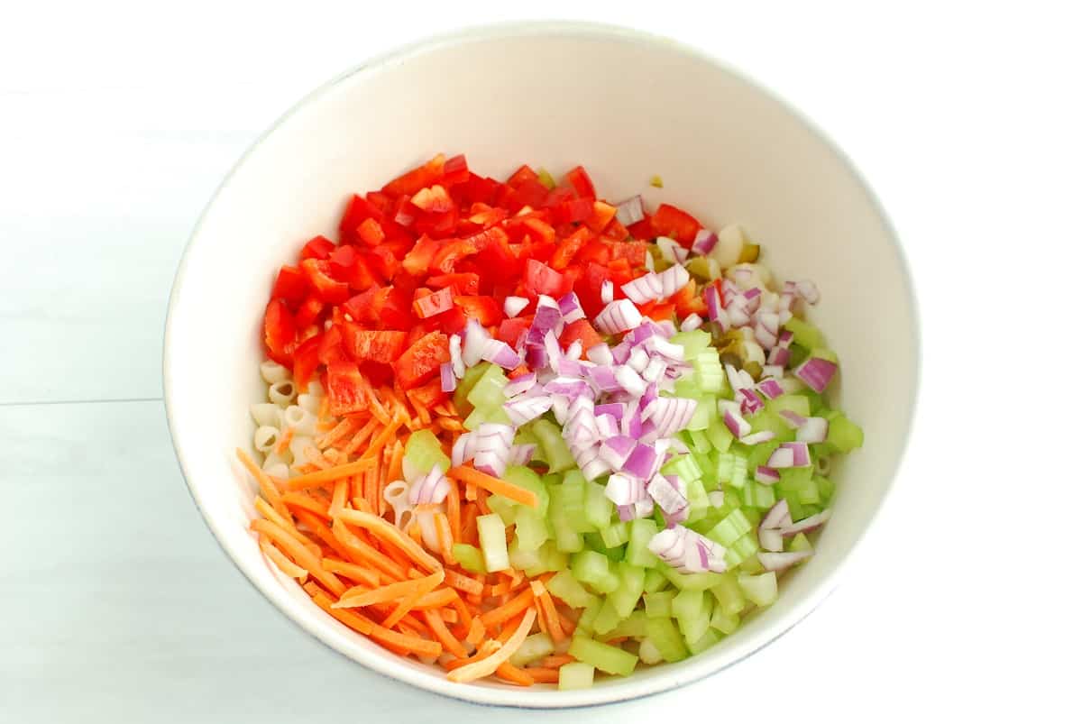 A bowl of macaroni with various veggies added to the bowl.