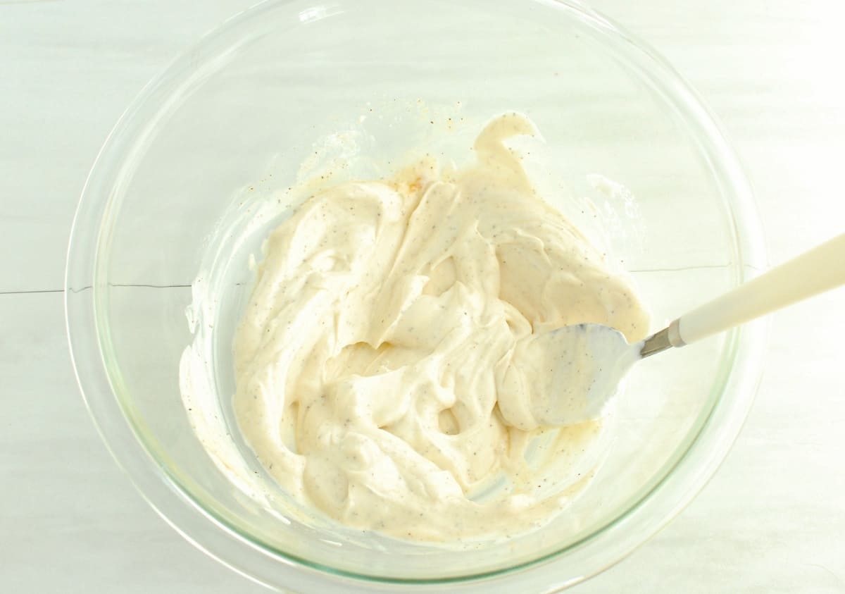 All of the greek yogurt sauce ingredients mixed together in a glass mixing bowl.