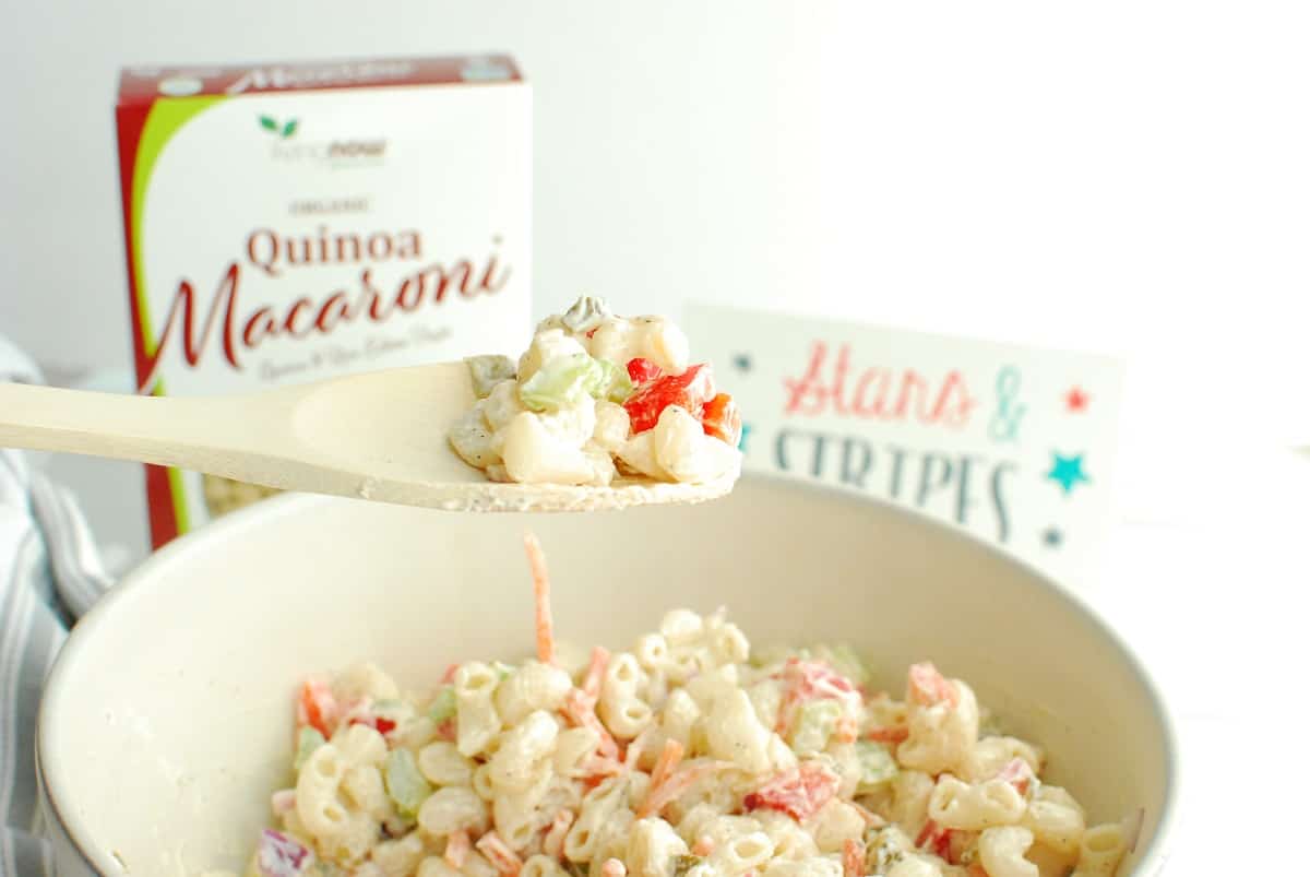 A wooden spoon scooping out greek yogurt macaroni salad.