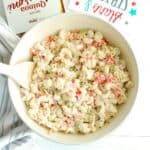 A bowl of greek yogurt macaroni salad with a wooden spoon in the side.